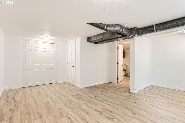 basement with a textured ceiling and light hardwood / wood-style flooring