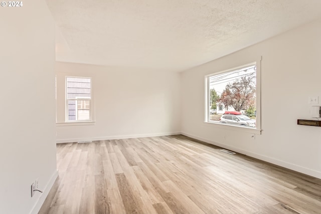 empty room with a textured ceiling and light wood-type flooring