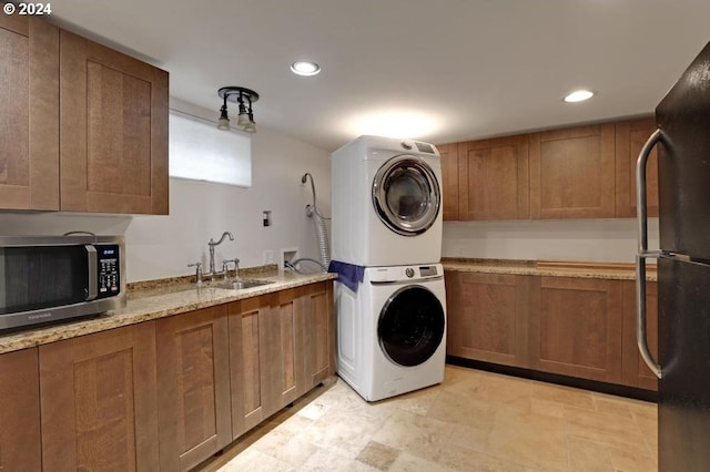 clothes washing area with stacked washing maching and dryer and sink