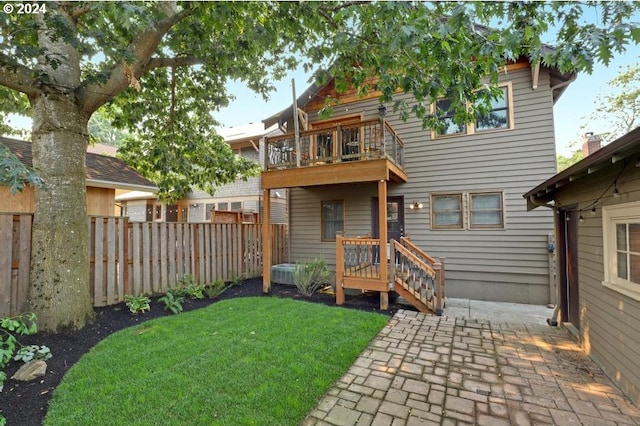 rear view of house with a lawn, a patio, and a balcony