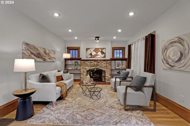 living room featuring wood-type flooring and a brick fireplace