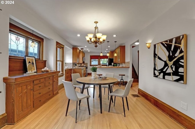 dining room with a wealth of natural light, a notable chandelier, and light hardwood / wood-style flooring