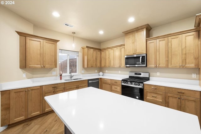 kitchen with appliances with stainless steel finishes, decorative light fixtures, light hardwood / wood-style flooring, and sink