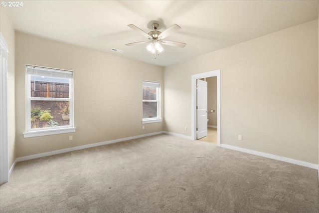 carpeted spare room with a wealth of natural light and ceiling fan