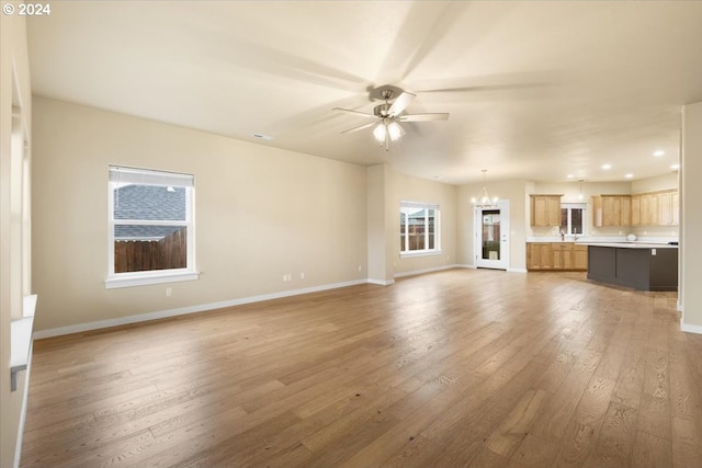 unfurnished living room featuring hardwood / wood-style floors and ceiling fan with notable chandelier