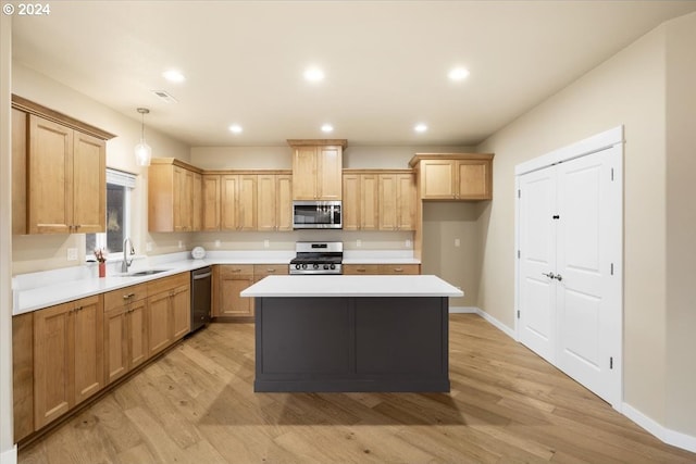 kitchen featuring sink, appliances with stainless steel finishes, pendant lighting, a kitchen island, and light wood-type flooring