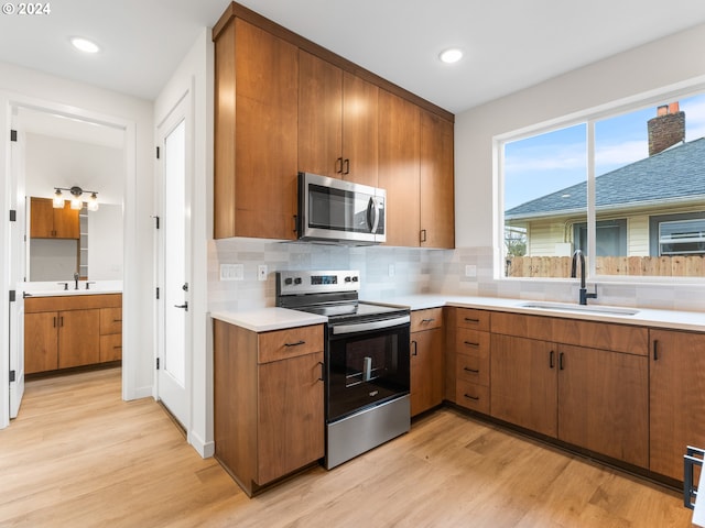 kitchen featuring tasteful backsplash, stainless steel appliances, light hardwood / wood-style floors, and sink