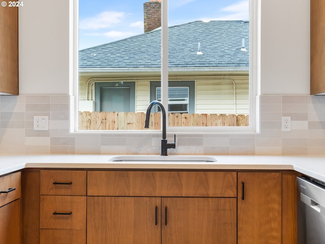 kitchen featuring stainless steel dishwasher, sink, and backsplash