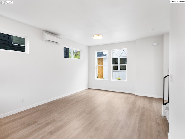 empty room featuring a wall mounted air conditioner and light hardwood / wood-style flooring