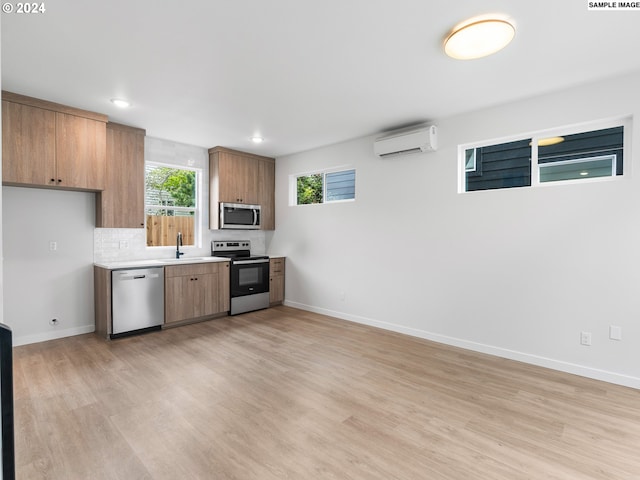 kitchen with sink, stainless steel appliances, light hardwood / wood-style flooring, an AC wall unit, and backsplash