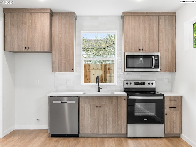 kitchen featuring appliances with stainless steel finishes, light hardwood / wood-style floors, a wealth of natural light, and sink