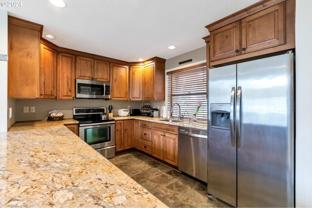 kitchen featuring dark tile floors, sink, stainless steel appliances, and light stone countertops