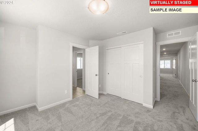 unfurnished bedroom with a closet, light carpet, and multiple windows