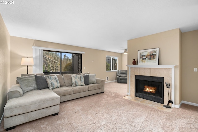 carpeted living room featuring ceiling fan and a tiled fireplace