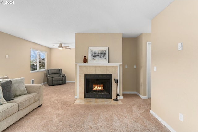 living room featuring a tile fireplace, light colored carpet, and ceiling fan