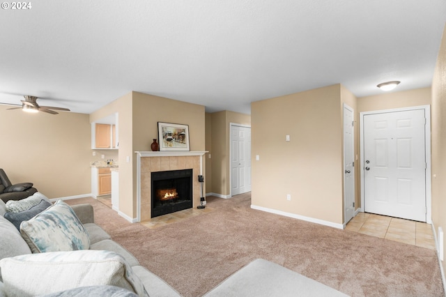 carpeted living room with ceiling fan and a tiled fireplace