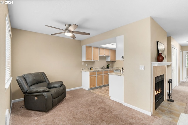 living area featuring light carpet, a tile fireplace, and ceiling fan