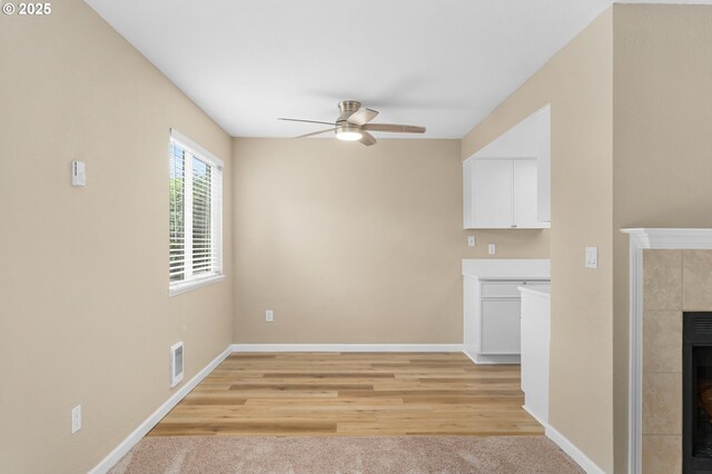 9480 SW 146th Ter Unit Q1, Beaverton, OR 97007 - unfurnished living room with a tile fireplace, a ceiling fan, baseboards, and light wood-style flooring