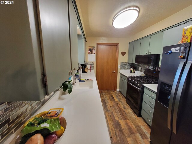 kitchen with sink, backsplash, dark wood-type flooring, and black appliances