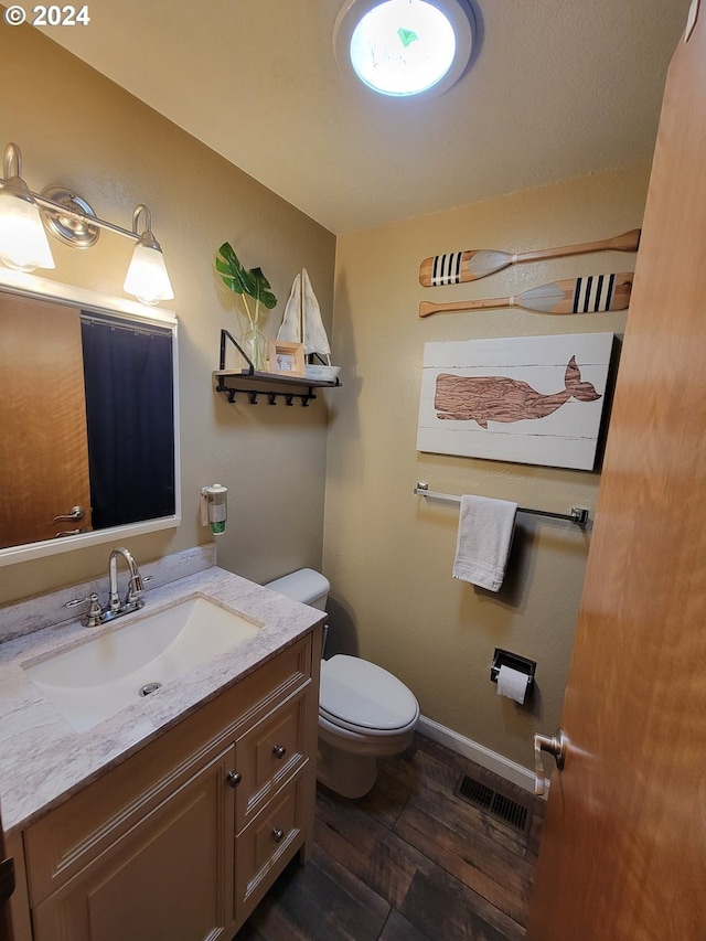 bathroom featuring wood-type flooring, vanity, and toilet