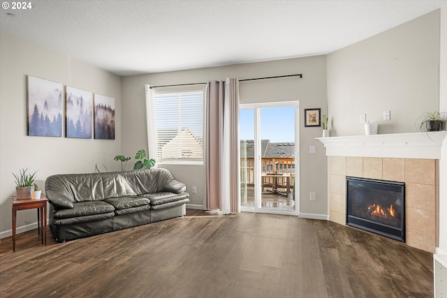 living room with a fireplace, dark wood-type flooring, and a textured ceiling