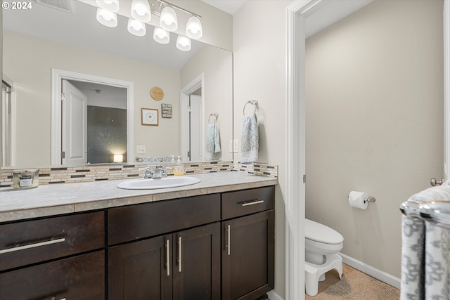 bathroom with vanity, toilet, and tasteful backsplash