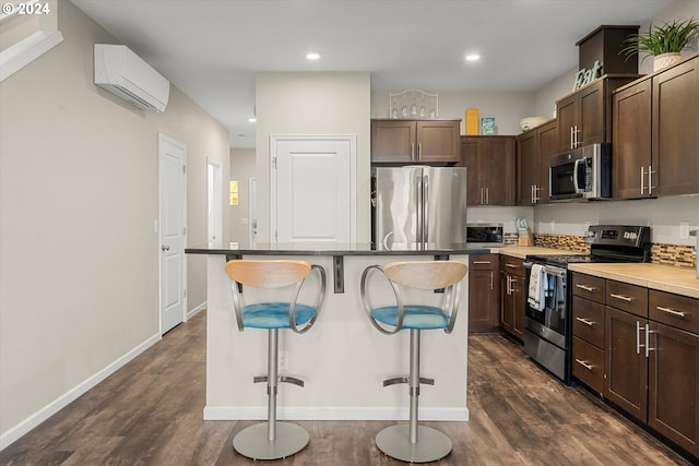 kitchen with a wall mounted air conditioner, a breakfast bar, dark wood-type flooring, appliances with stainless steel finishes, and a kitchen island