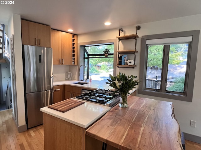 kitchen featuring light wood-type flooring, stainless steel fridge, sink, and a wealth of natural light