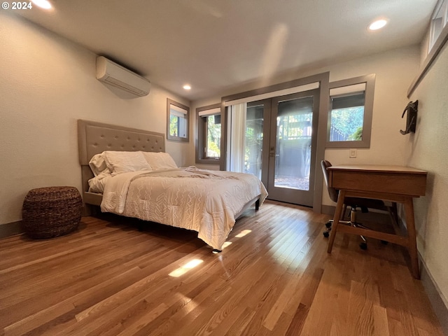 bedroom with access to outside, french doors, a wall unit AC, and hardwood / wood-style flooring