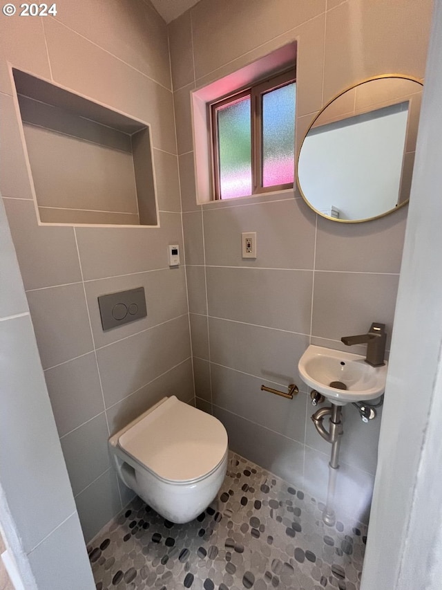 bathroom with tile walls, tile patterned flooring, toilet, and sink