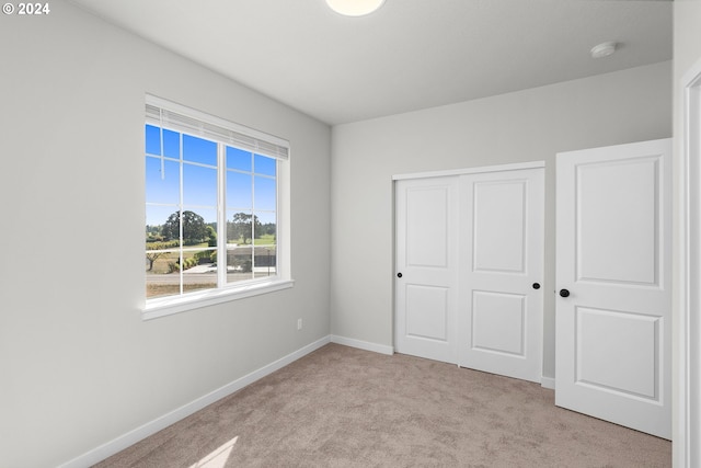 unfurnished bedroom featuring light carpet and a closet