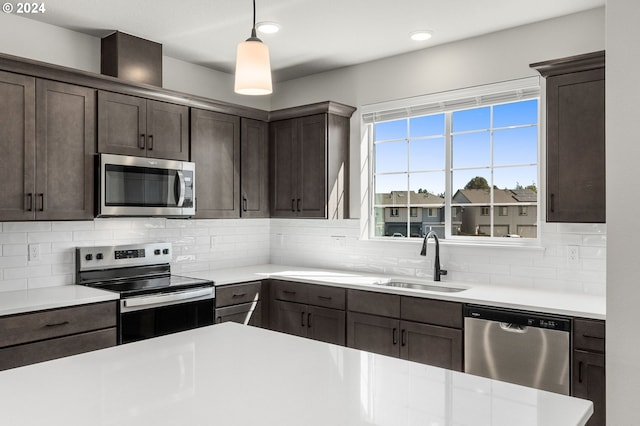 kitchen with backsplash, dark brown cabinetry, stainless steel appliances, sink, and hanging light fixtures