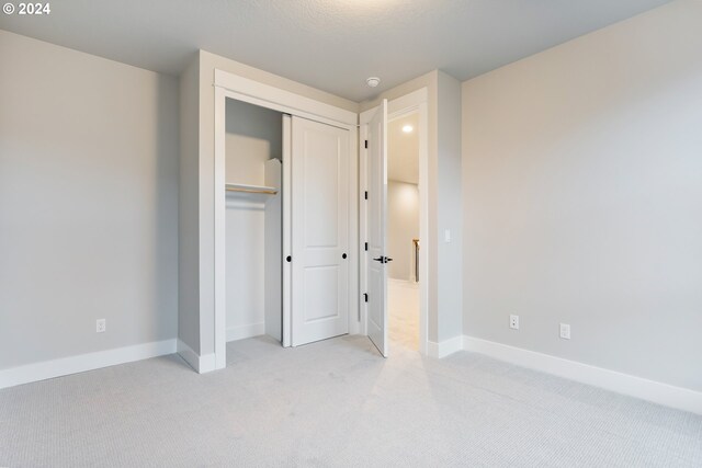 unfurnished bedroom featuring a closet and light colored carpet