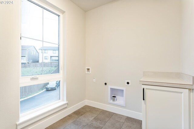 clothes washing area featuring hookup for an electric dryer, a healthy amount of sunlight, and light tile patterned floors