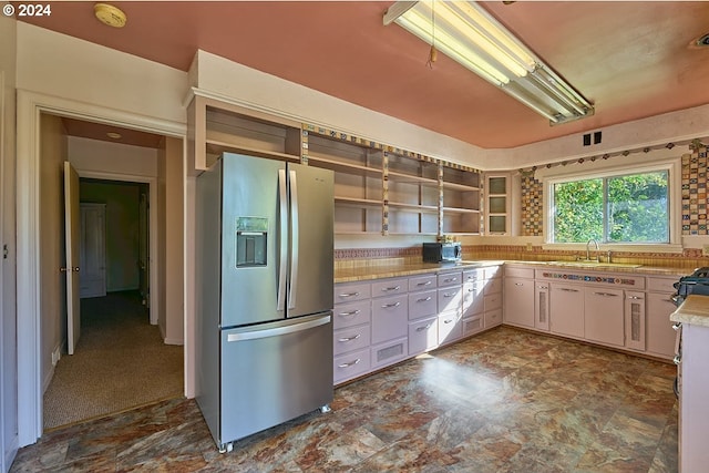 kitchen featuring white cabinets, sink, stainless steel fridge with ice dispenser, dark colored carpet, and black stove