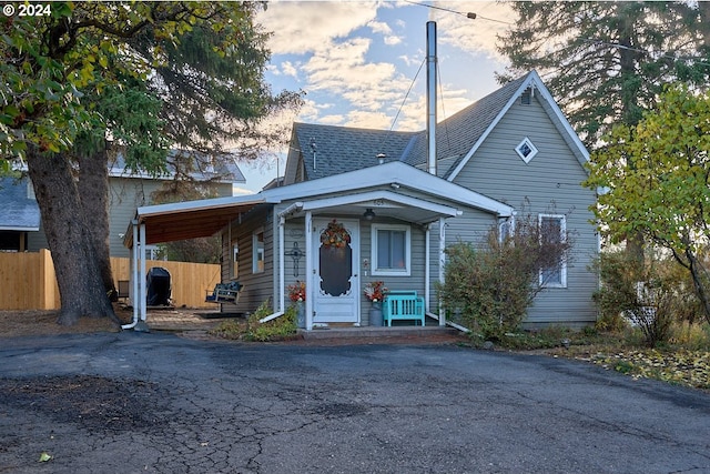 view of front of property with fence, roof with shingles, and aphalt driveway