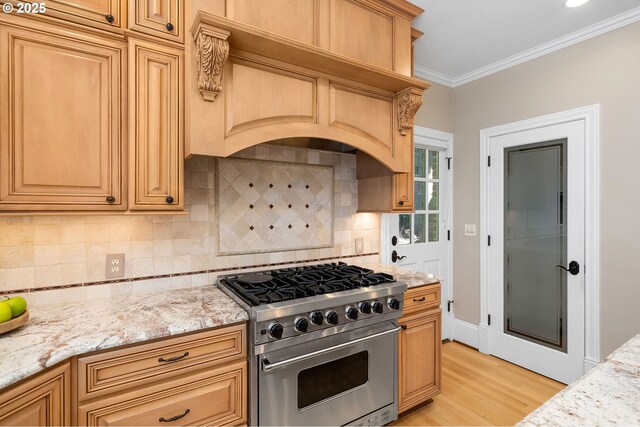 4243 SW Bertha Ave, Portland, OR 97239 - kitchen with high end stove, light wood finished floors, light stone counters, backsplash, and crown molding