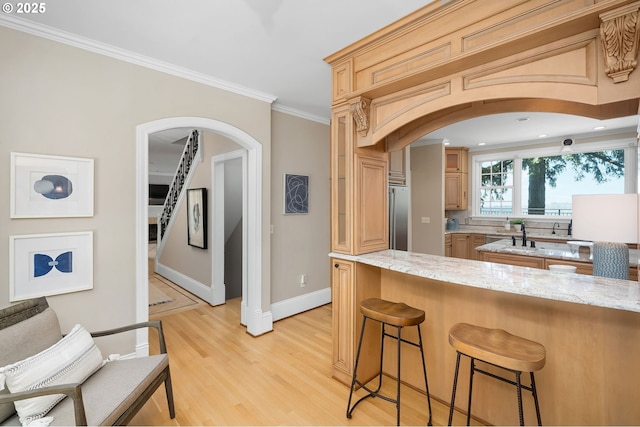 4243 SW Bertha Ave, Portland, OR 97239 - kitchen with arched walkways, high quality fridge, a breakfast bar, light wood-style flooring, and ornamental molding