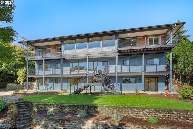 rear view of house with a balcony and a yard