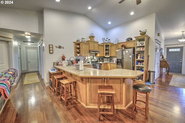 kitchen featuring dark wood-type flooring, a breakfast bar area, kitchen peninsula, and appliances with stainless steel finishes