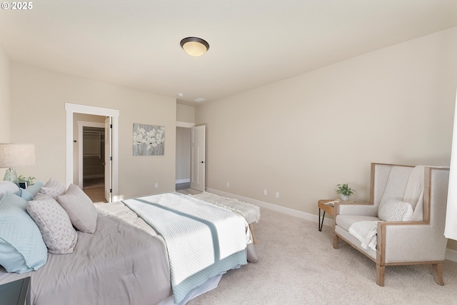 bedroom featuring light carpet, a spacious closet, and baseboards