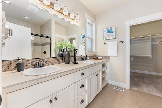 bathroom featuring backsplash, vanity, and an enclosed shower