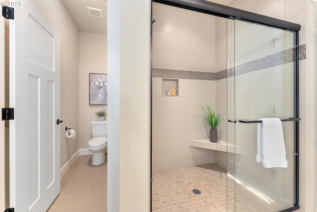 bathroom featuring tile patterned flooring, toilet, and a shower with shower door