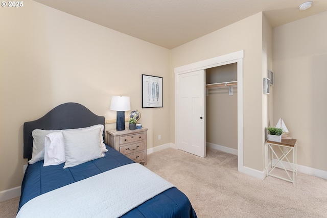 bedroom with a closet, light colored carpet, and baseboards