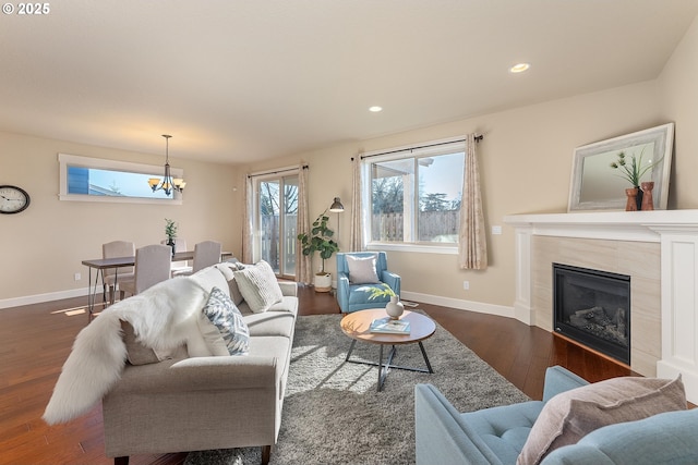 living room featuring dark hardwood / wood-style flooring, an inviting chandelier, and a tiled fireplace