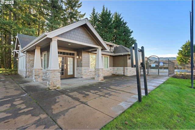 view of front of property with stone siding, french doors, fence, and a gate