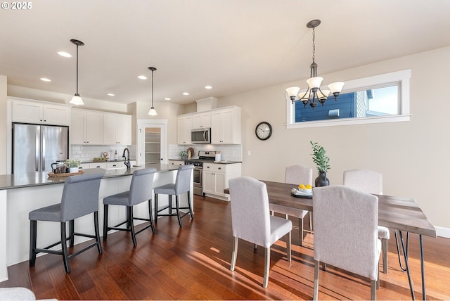 dining area with dark hardwood / wood-style floors, an inviting chandelier, and sink