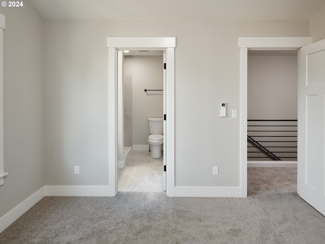 unfurnished bedroom featuring light colored carpet and ensuite bath