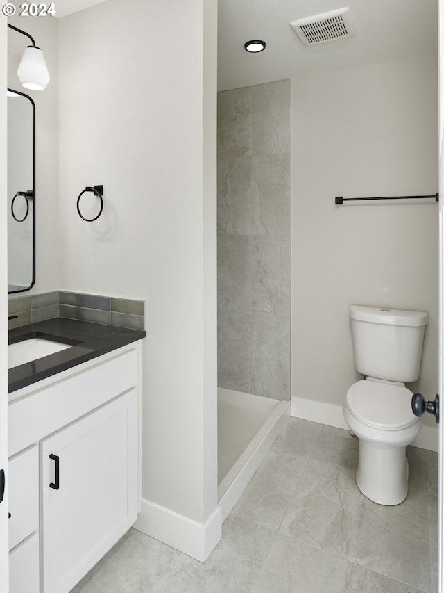 bathroom featuring a shower, toilet, tile floors, and vanity