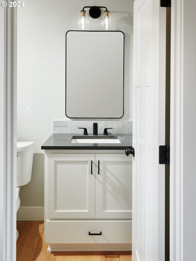 bathroom with toilet, oversized vanity, and hardwood / wood-style flooring